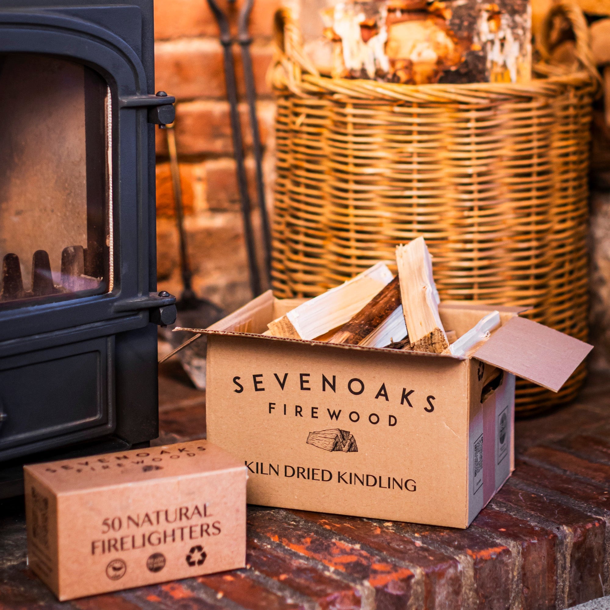 Box of Sevenoaks Firewood kindling  and firelighters in front of a fireplace.